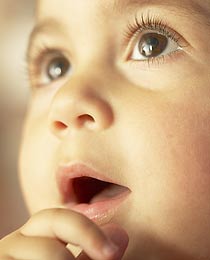 photo of an infant about to insert her thumb into her mouth